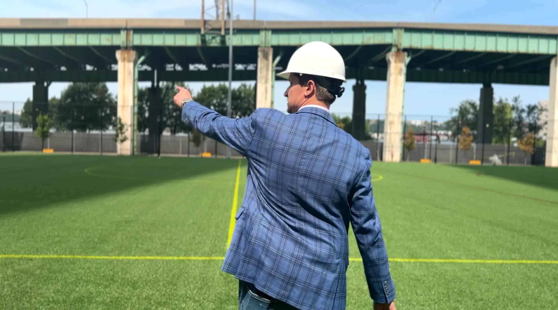 Jason Pancoast, P.E. pointing out site conditions on a sports field beneath an elevated highway structure